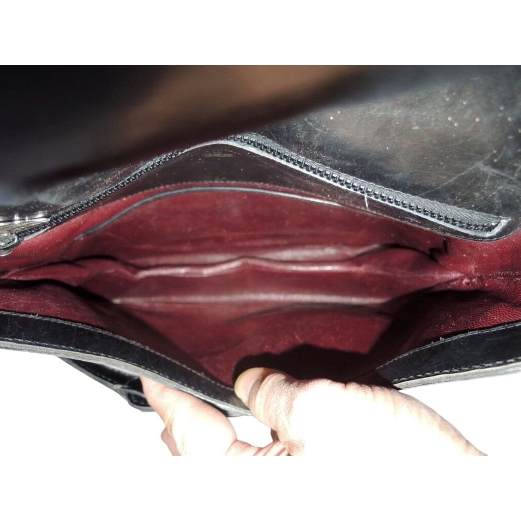 1970s GCCI saddle bag in black leather with muted gold hardware, an expandable bottom, wide shoulder strap, and burgundy leather lining